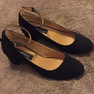 Low black heels with ankle strap.